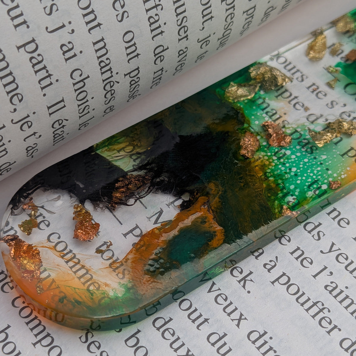 Bottom rounded end of handmade green gold resin bookmark on book page – EL-Creations