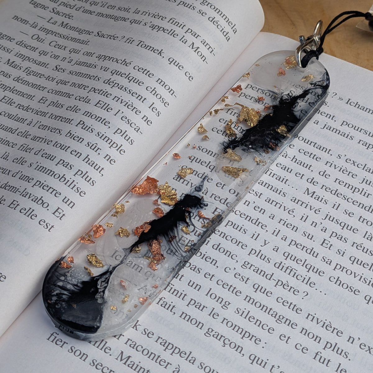 Full length handmade black gold resin bookmark lying on open French book – EL-Creations