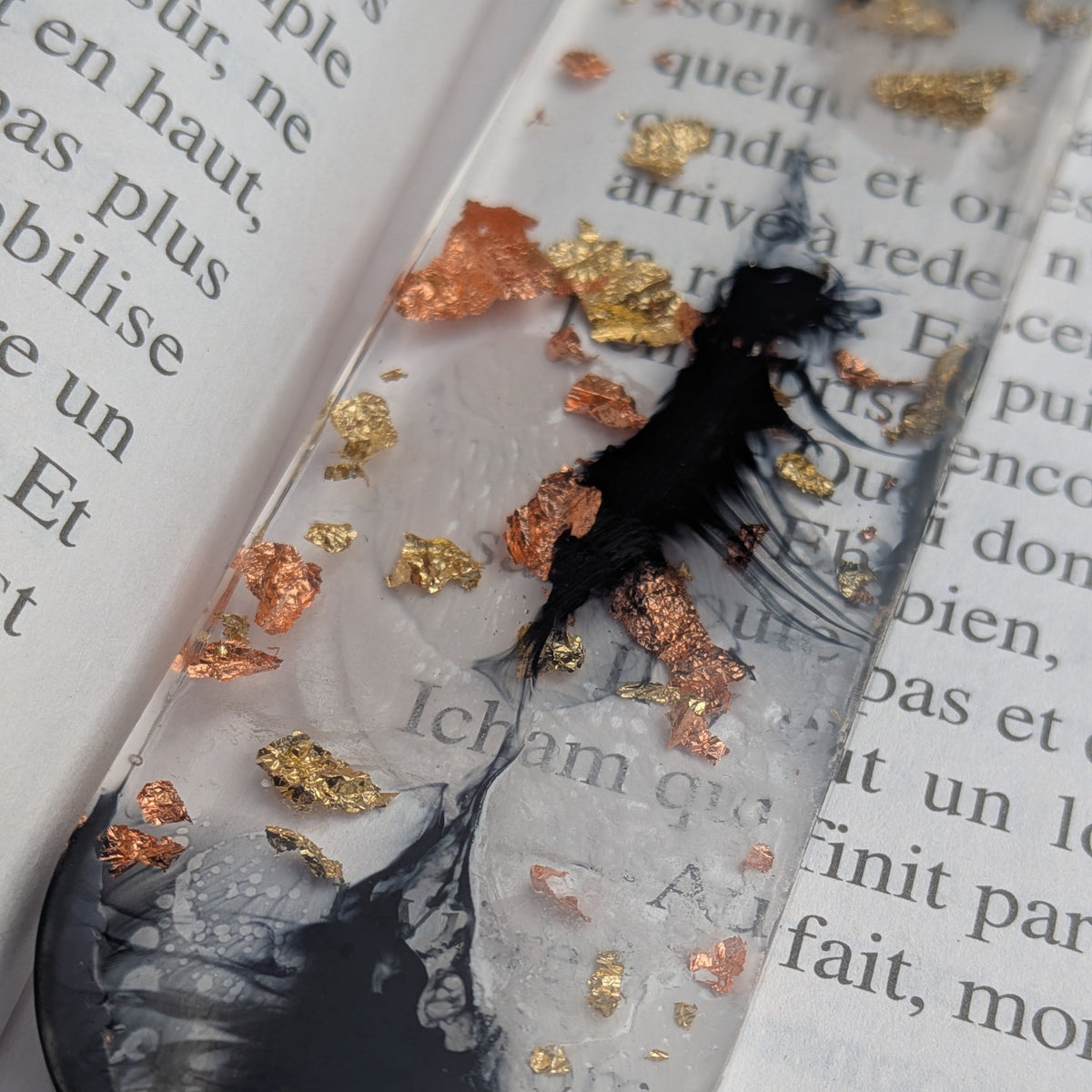 Macro close-up of black ink swirl with copper and gold leaf in clear resin bookmark – EL-Creations