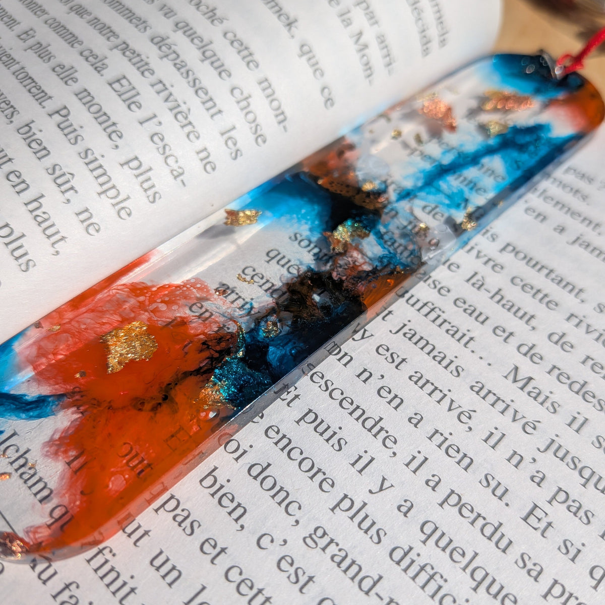 Detail macro of blazing orange swirl with gold leaf in blue epoxy resin bookmark – EL-Creations
