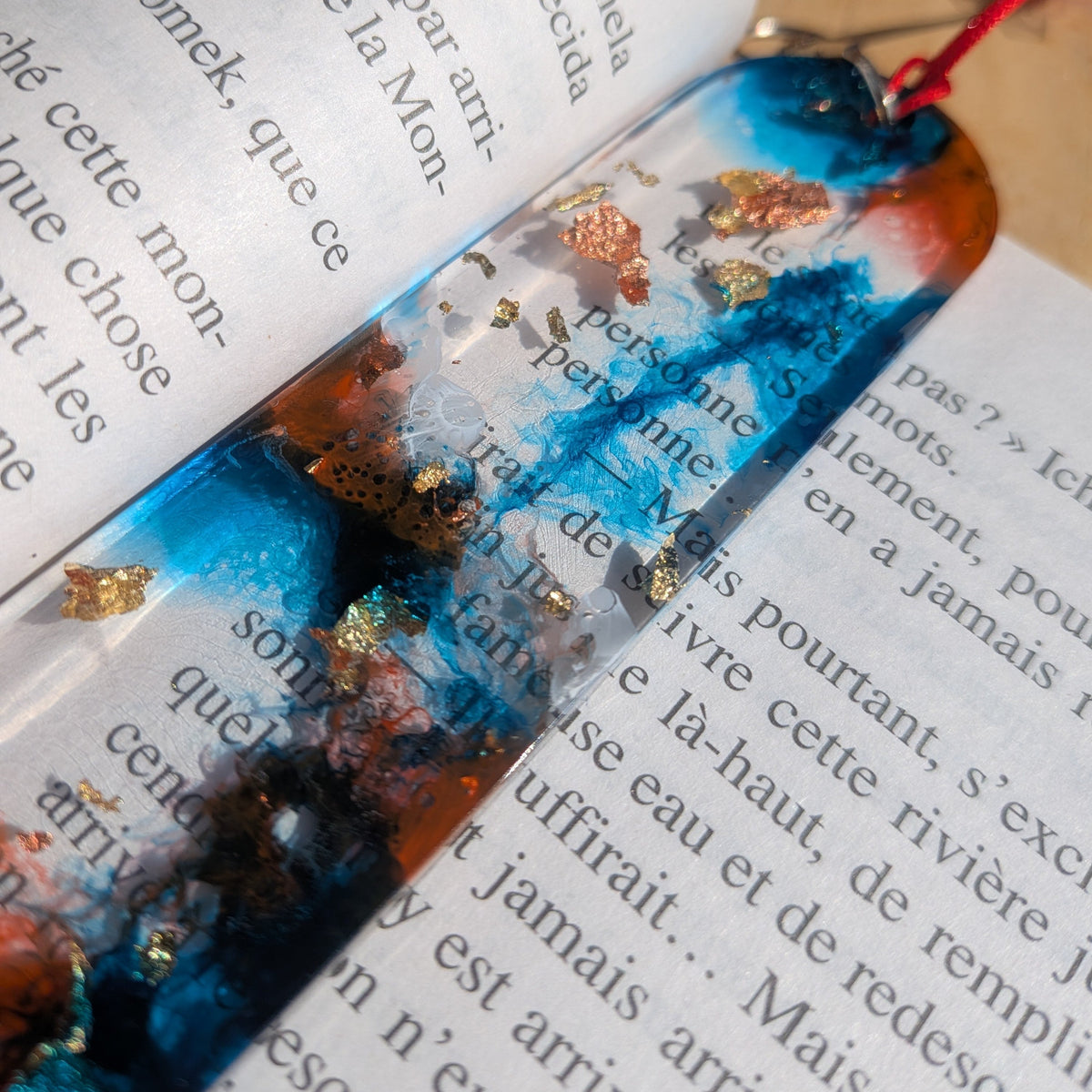 Close-up of blue and white foam swirl with copper leaf in handmade resin bookmark – EL-Creations