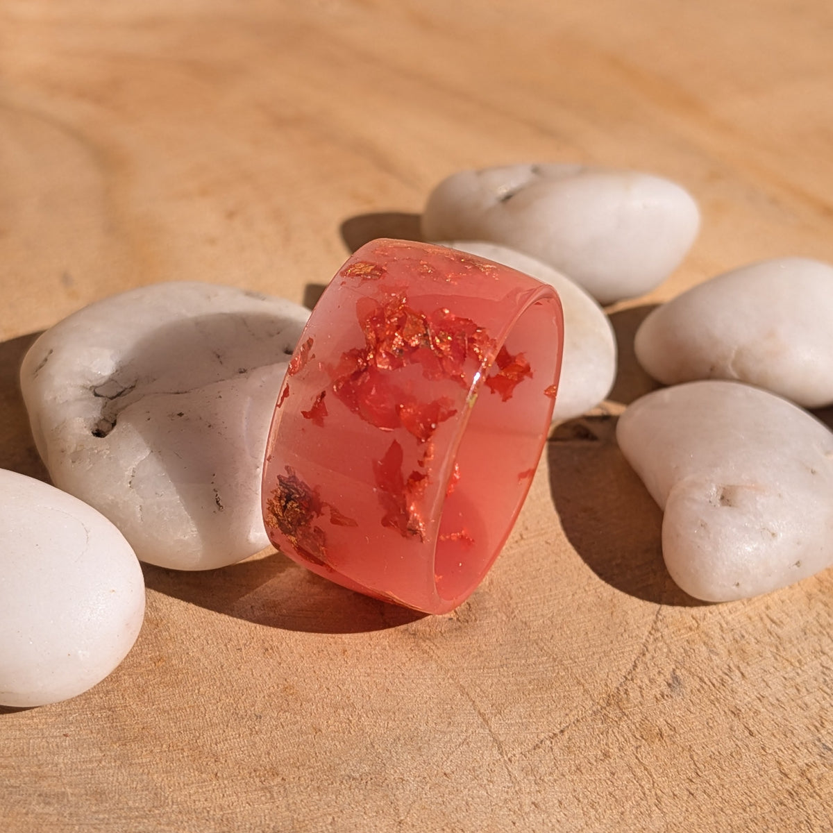 Side view of a chunky milky pink resin ring standing at an angle, with copper flakes visible through the glossy band, EL-Creations
