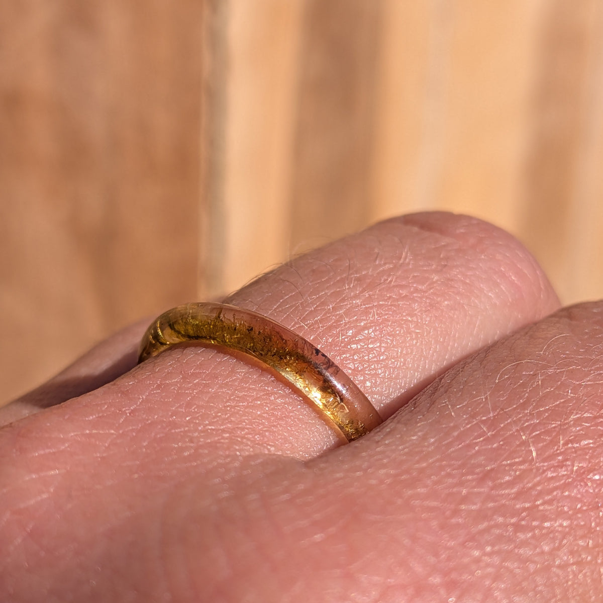 Low side view of a delicate botanical resin ring worn on a finger, showing moss inside the slender band, EL-Creations