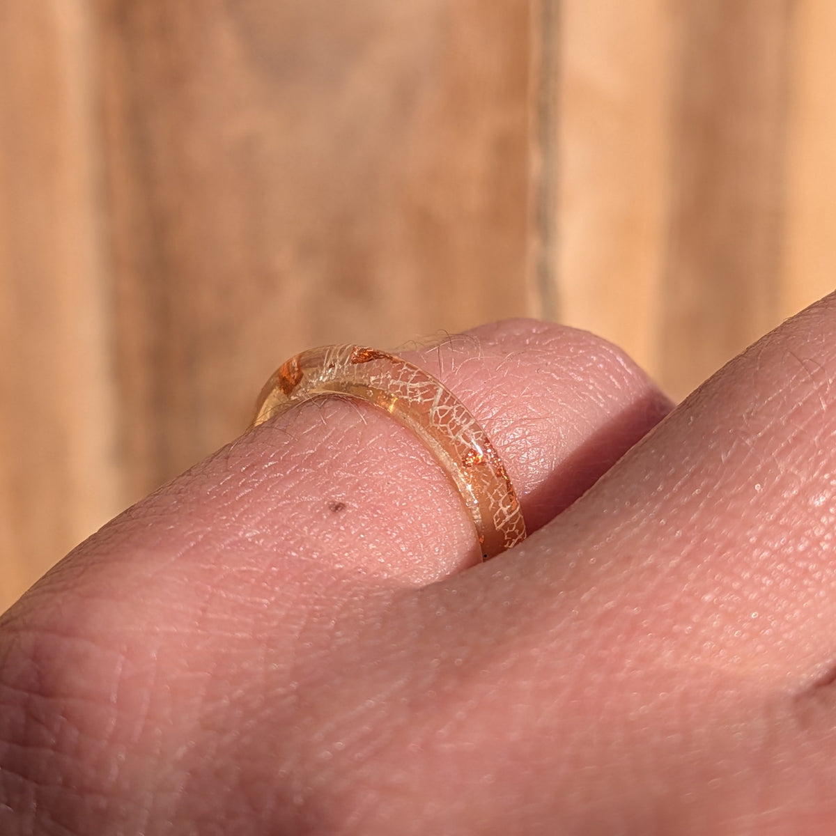 Side view of a slim white skeleton leaf resin ring with copper flakes worn on a gently bent finger, EL-Creations