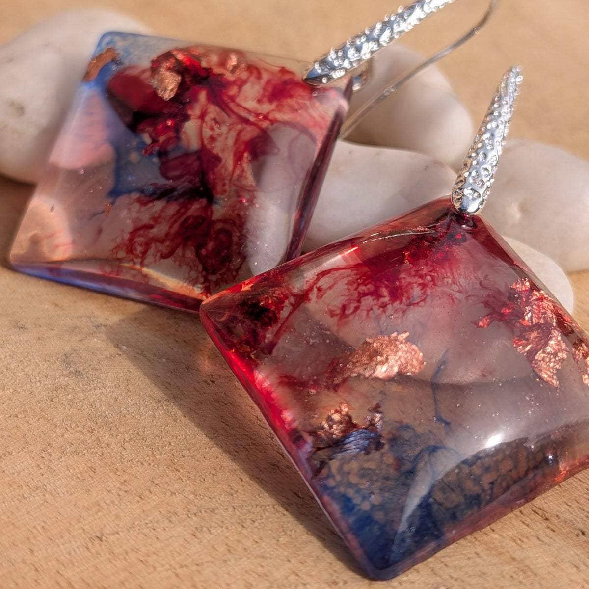 Macro view of crimson blue resin earrings with warm metallic-coloured details, EL-Creations