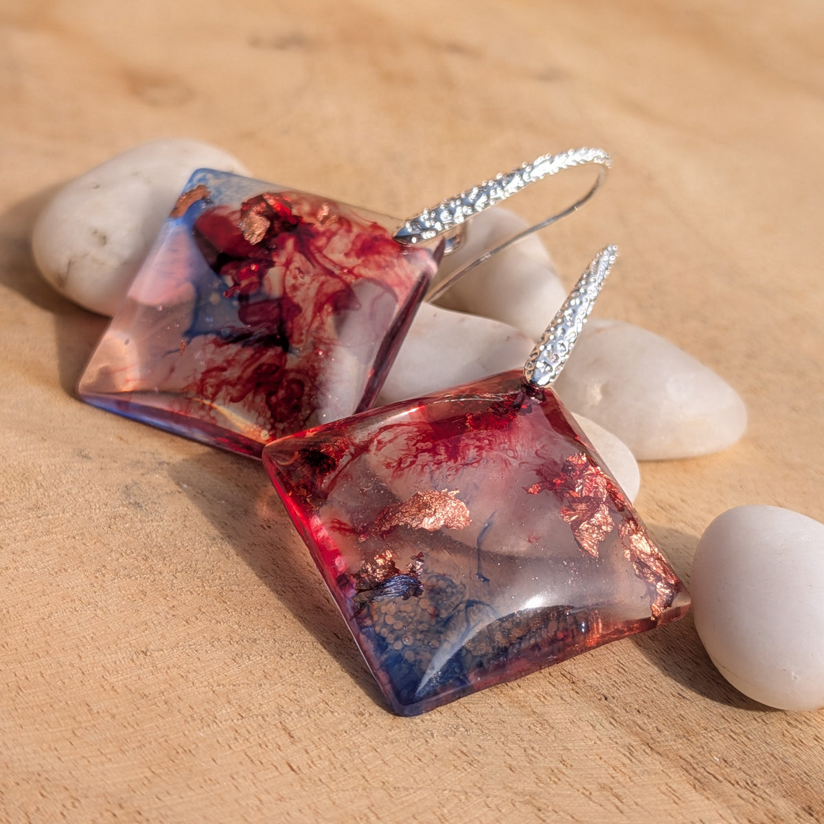 Angled view of square resin earrings showing glossy surfaces and silver hooks, EL-Creations