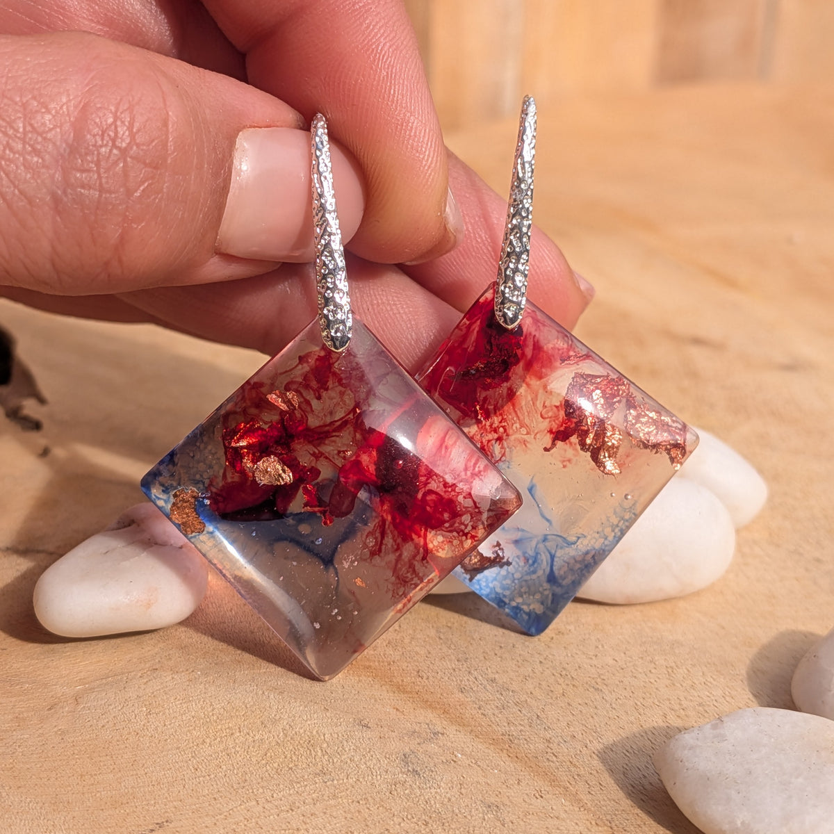 Front view of translucent crimson blue square earrings held by their silver hooks, EL-Creations