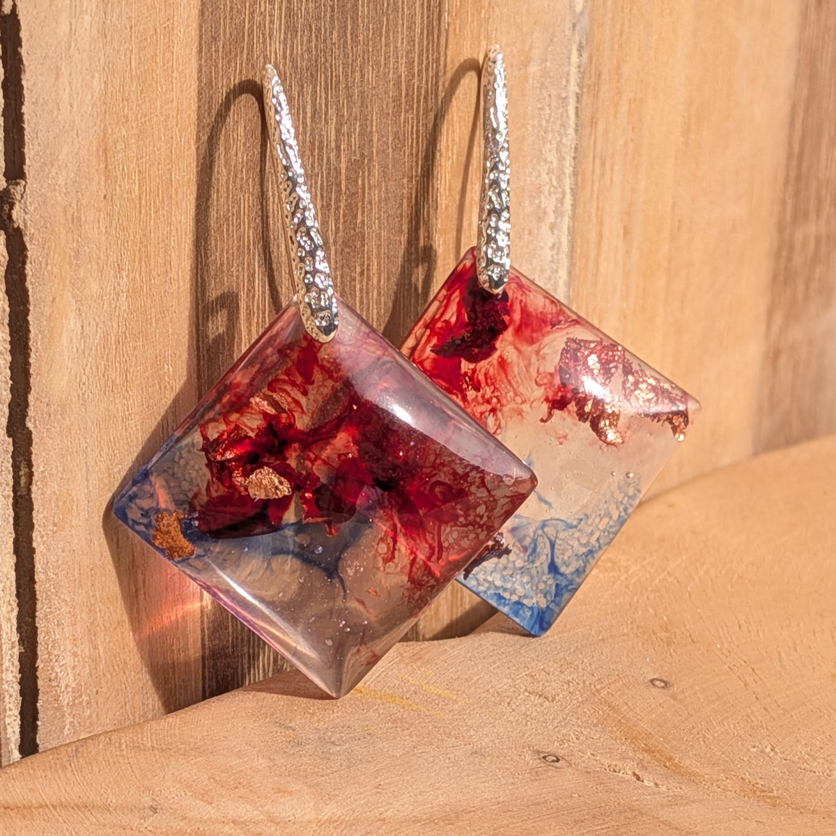 Crimson and blue square resin earrings with silver hooks against wood, EL-Creations