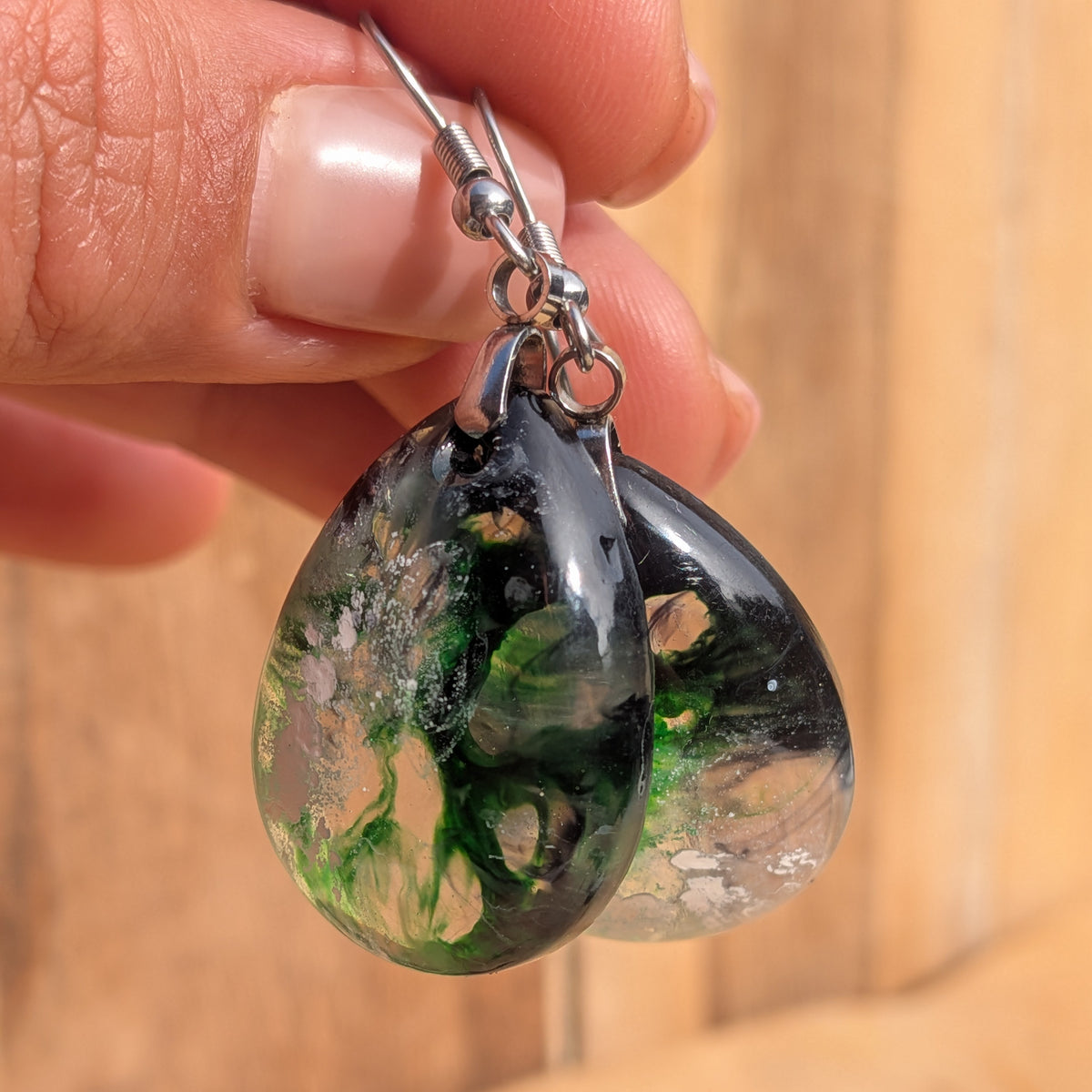Angled view of green black resin drops showing their glossy curved surfaces, EL-Creations