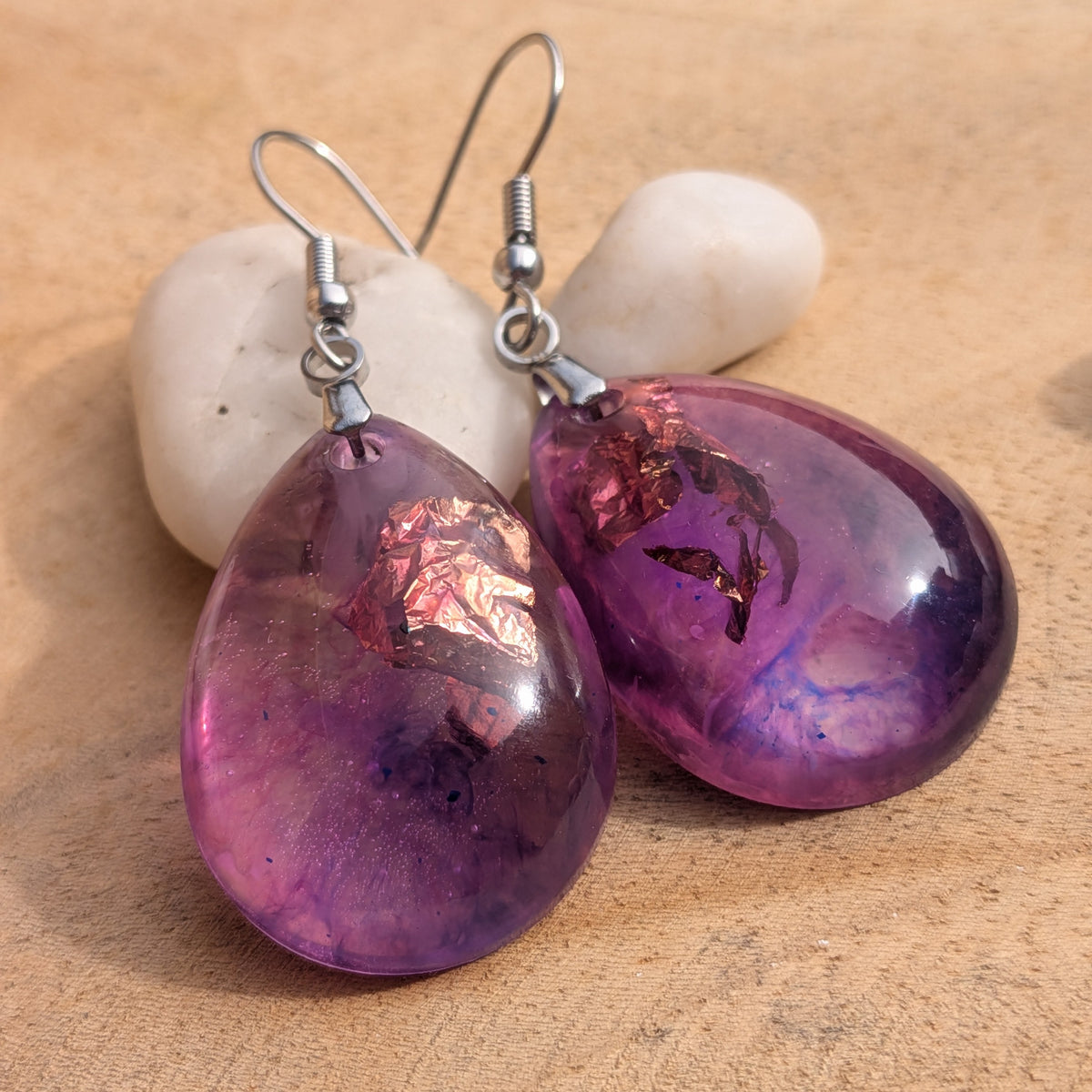 Pair of purple pink teardrop resin earrings displayed on wood with white stones, EL-Creations