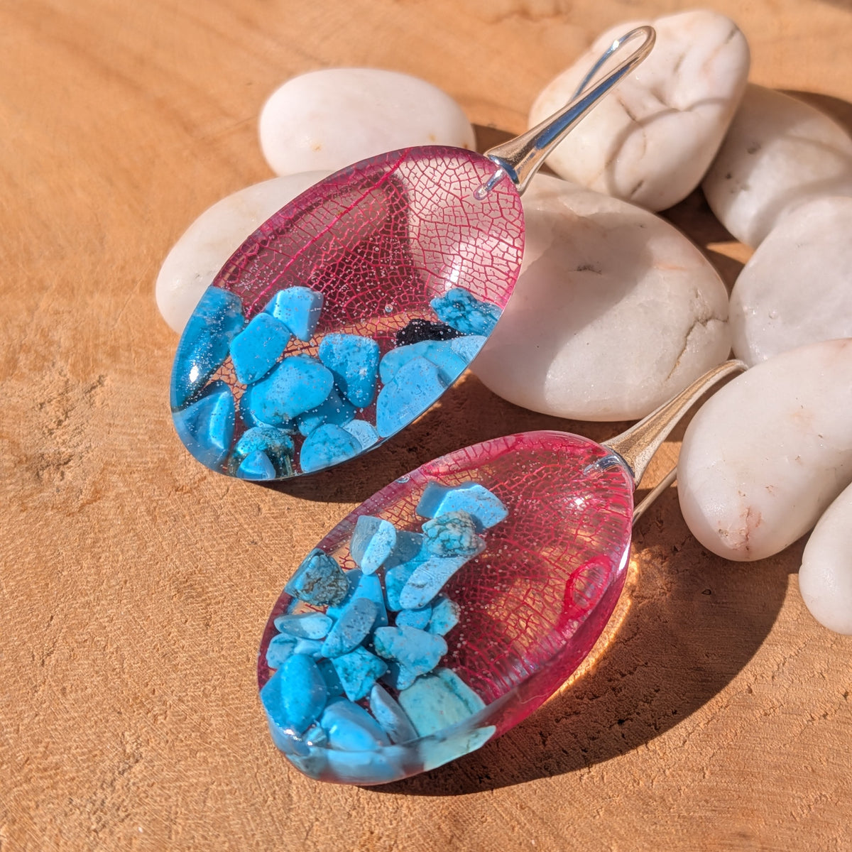 Close-up of intricate red leaf patterns and genuine turquoise chips in glossy resin earrings, EL-Creations