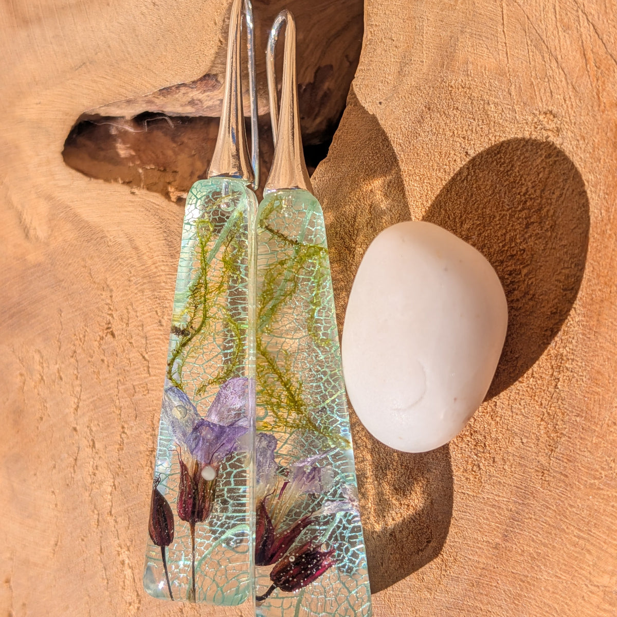 Close front view of tapered botanical earrings with light blue leaf veins and green moss, EL-Creations
