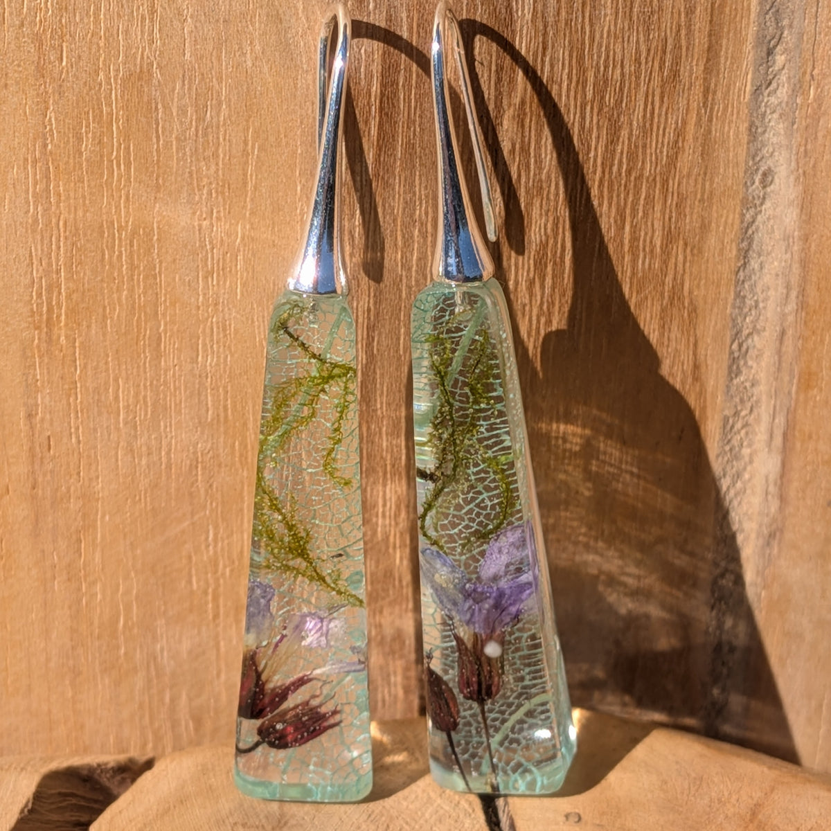 Close-up of light blue leaf veins and green moss preserved in glossy resin drop earrings, EL-Creations