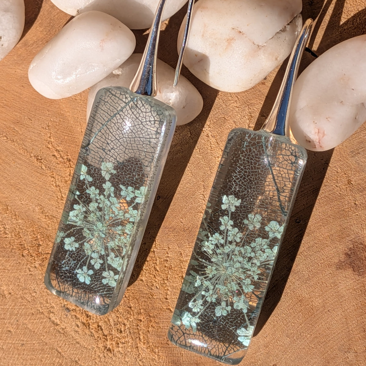 Macro view of Queen Anne's lace blossoms layered over skeleton leaf veins in resin earrings, EL-Creations