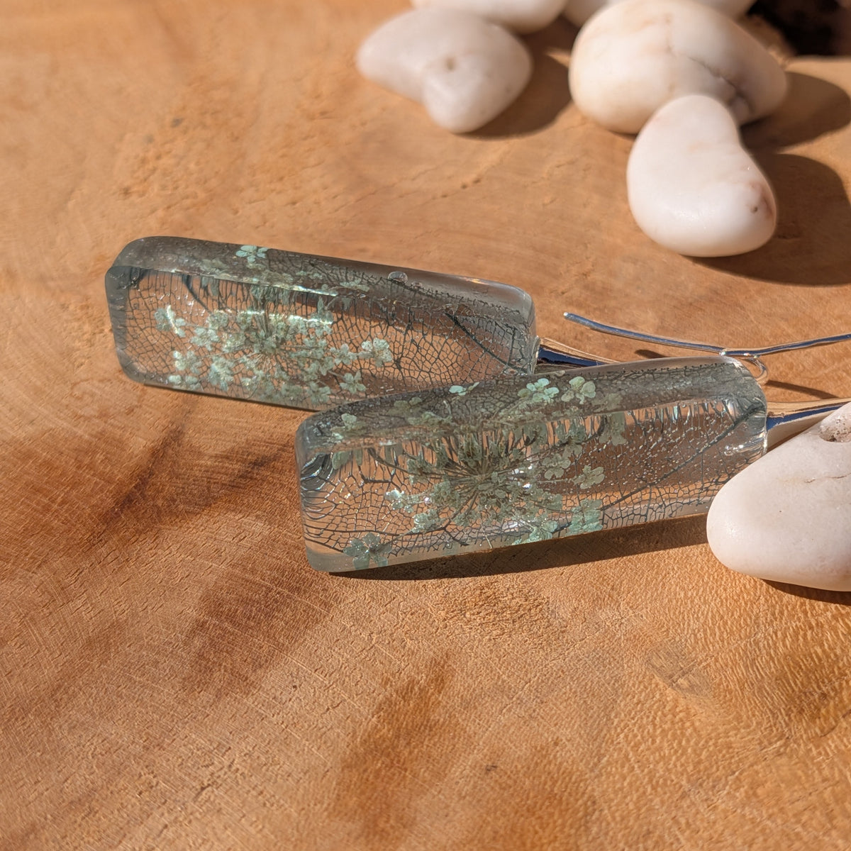 Rectangular Queen Anne's lace and skeleton leaf resin earrings standing against a wooden background, EL-Creations⠋