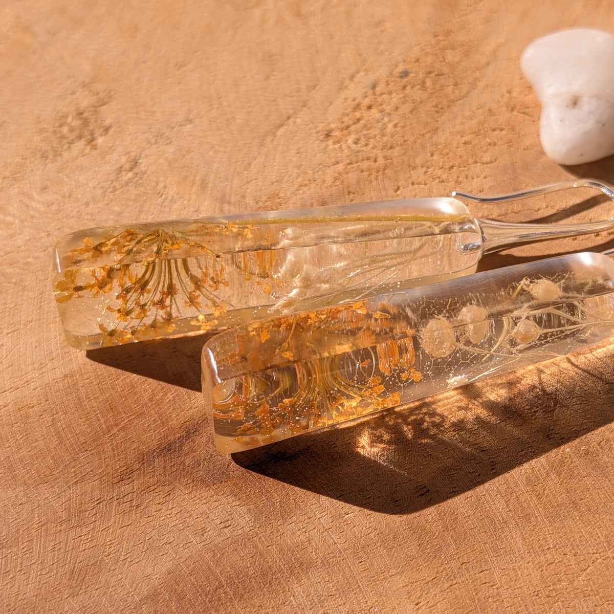 Long botanical resin earrings with Queen Anne's lace and pale wildflowers lying on wood, EL-Creations