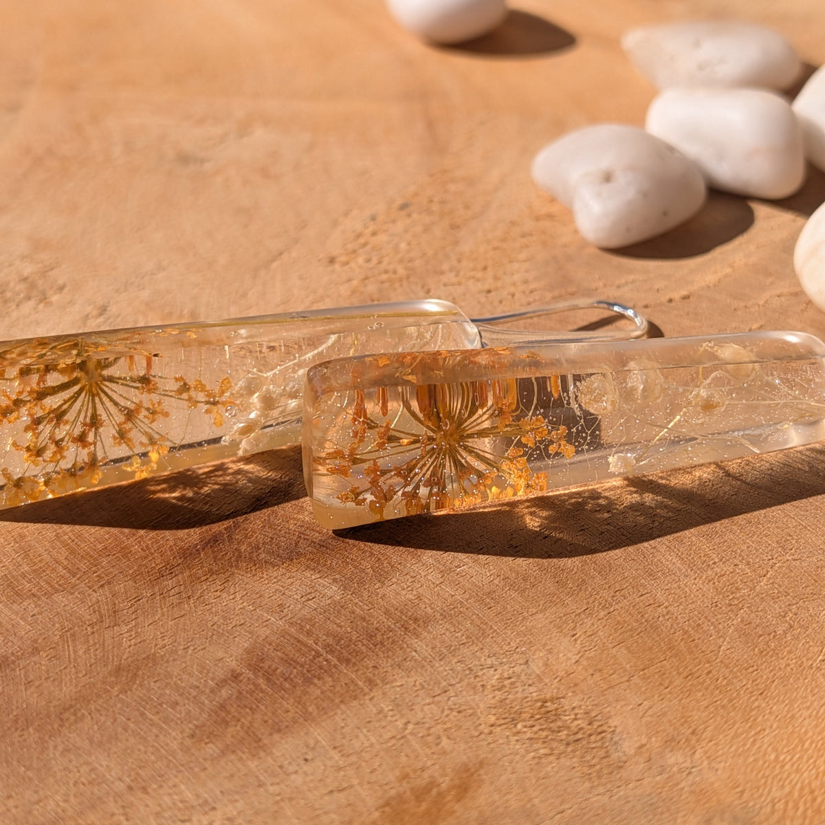 Close-up of golden flowers and delicate skeleton leaf patterns inside clear resin earrings, EL-Creations