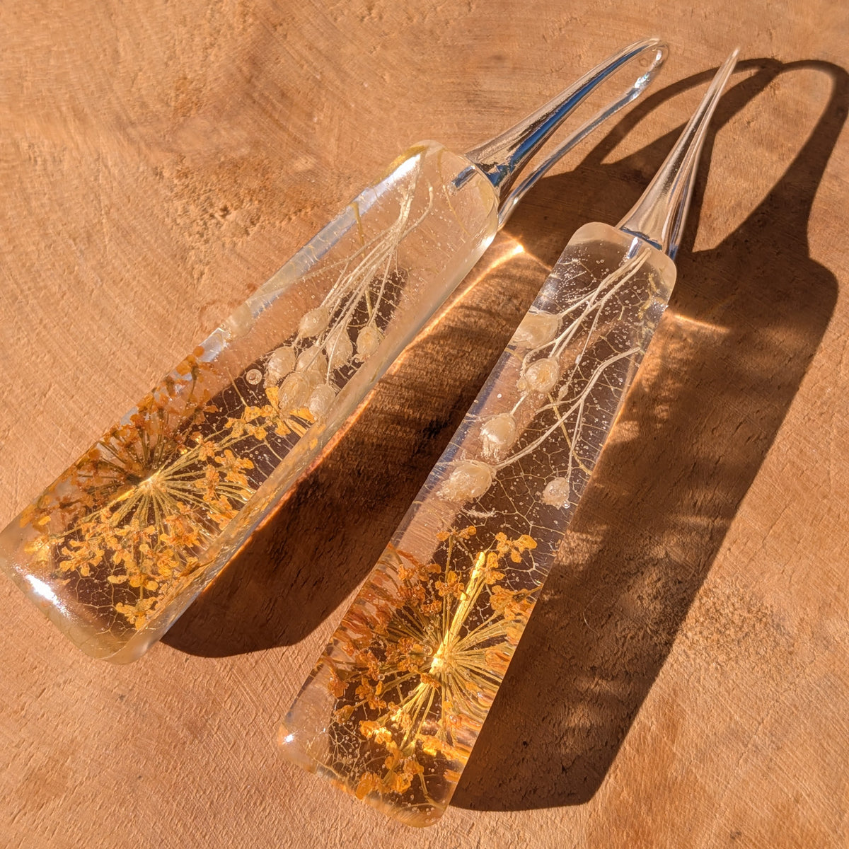 Angled view of autumn wildflower resin earrings with silver-tone hooks on a wooden surface, EL-Creations