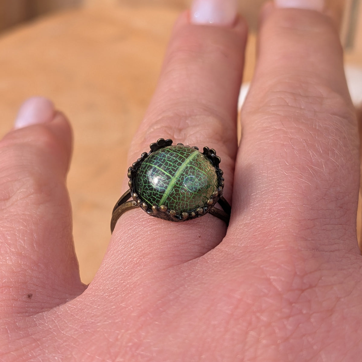 Adjustable Forest Lace resin ring worn on a finger, showing its intricate green leaf pattern and brown split band, EL-Creations
