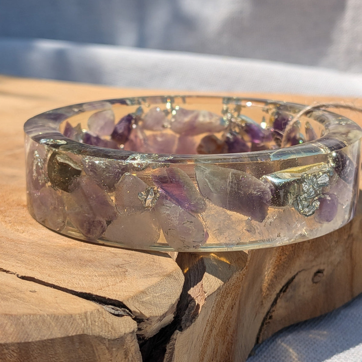 Wide amethyst crystal resin cuff bracelet standing on natural wood by EL-Creations