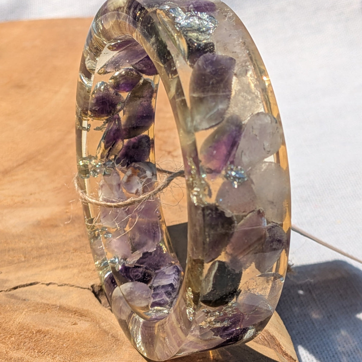 Purple amethyst and silver flake resin bangle resting on wood by EL-Creations