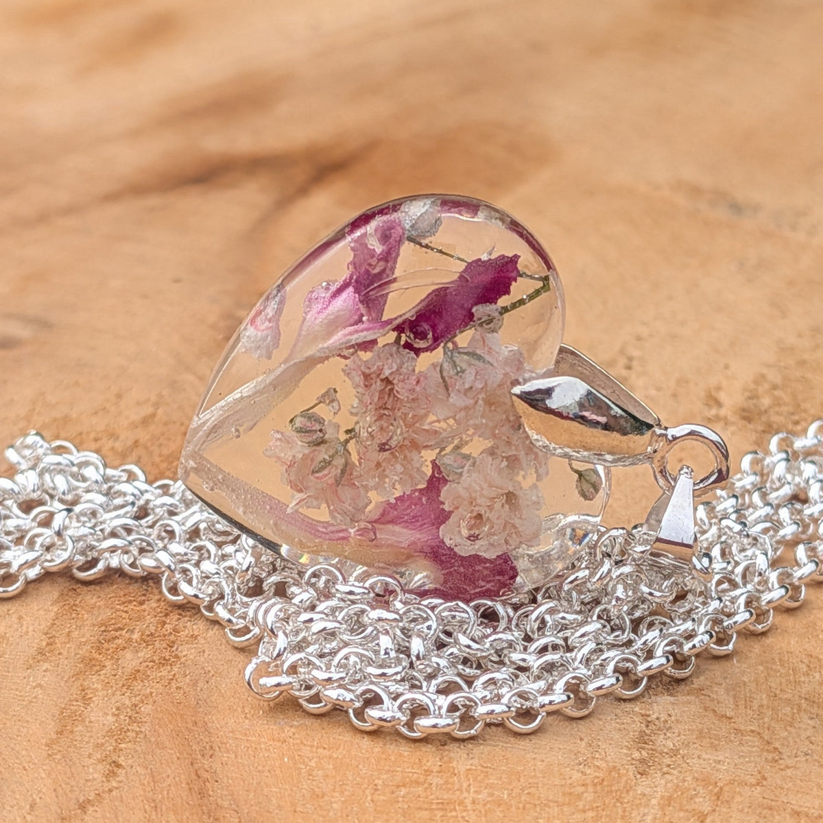 Handmade baby's breath carnation heart necklace resting on natural wood by EL-Creations