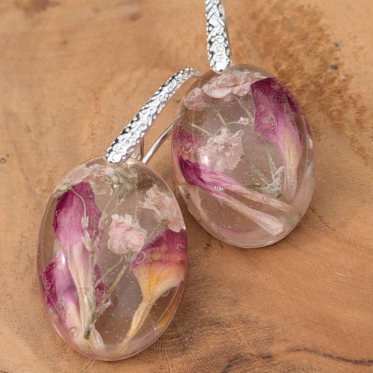 Close-up of baby's breath and carnation petals inside oval resin earrings by EL-Creations