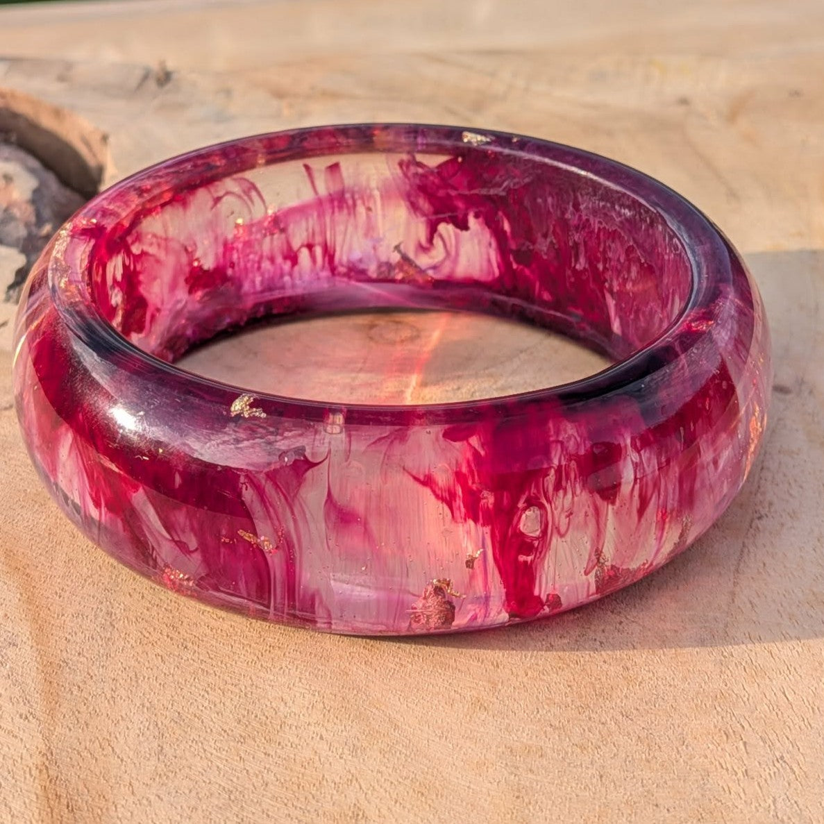 Side angle of burgundy rose gold resin bangle on wooden surface in natural light – EL-Creations