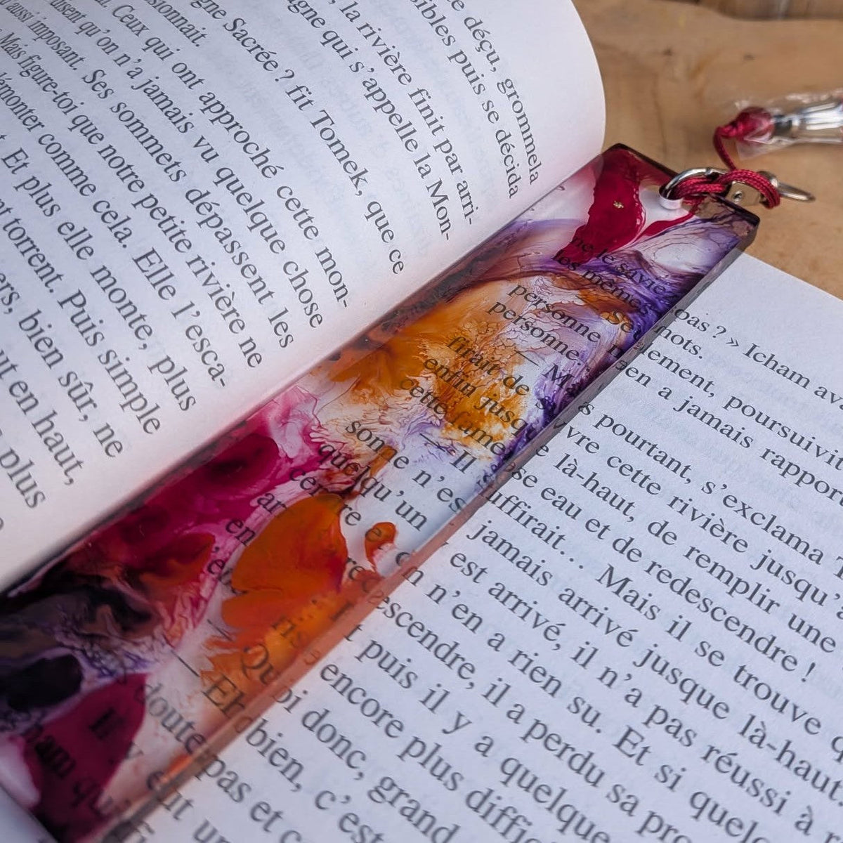 Side angle of crimson purple resin bookmark on open book showing mirror-polish finish – EL-Creations