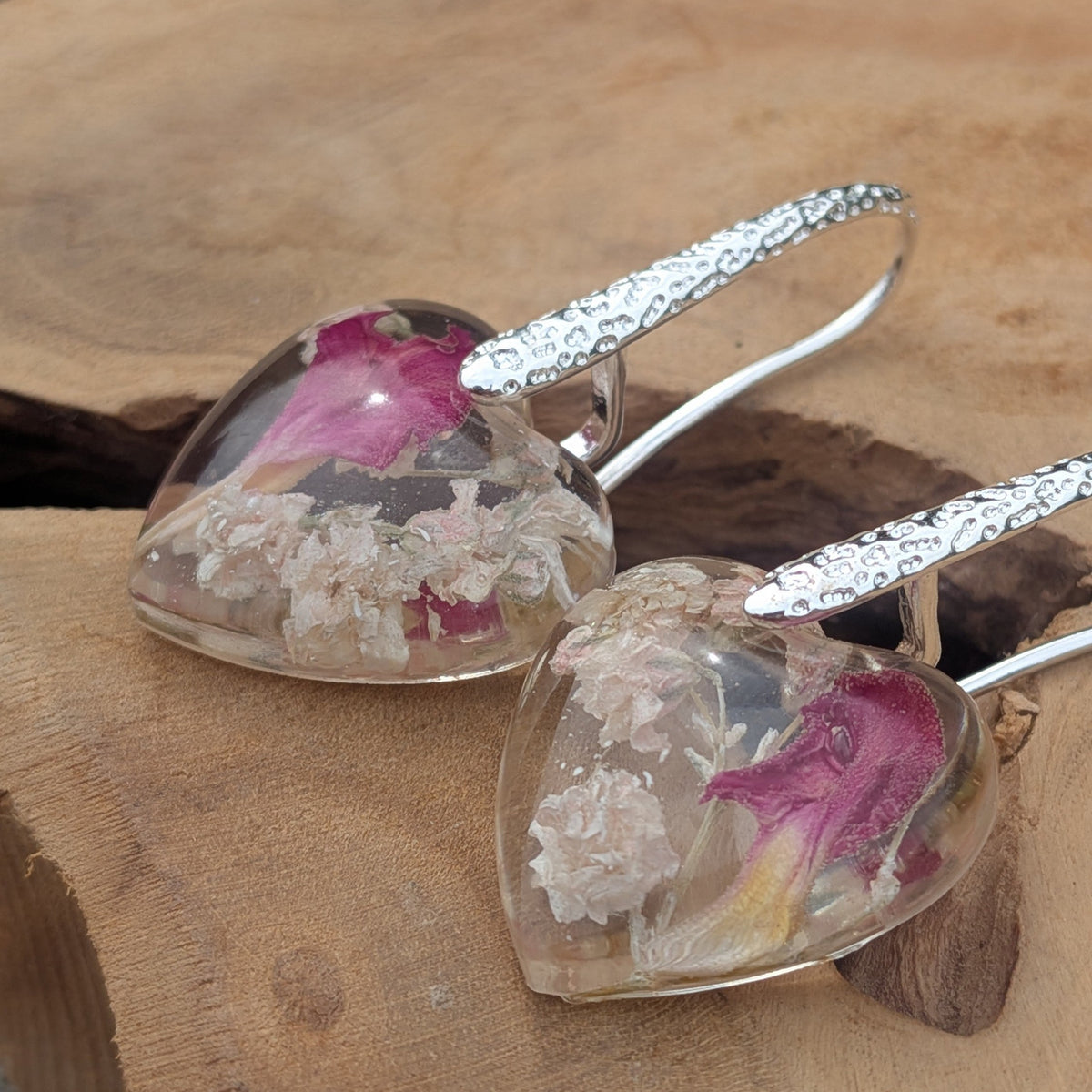 Close-up of baby's breath and carnation petal inside heart resin earrings by EL-Creations