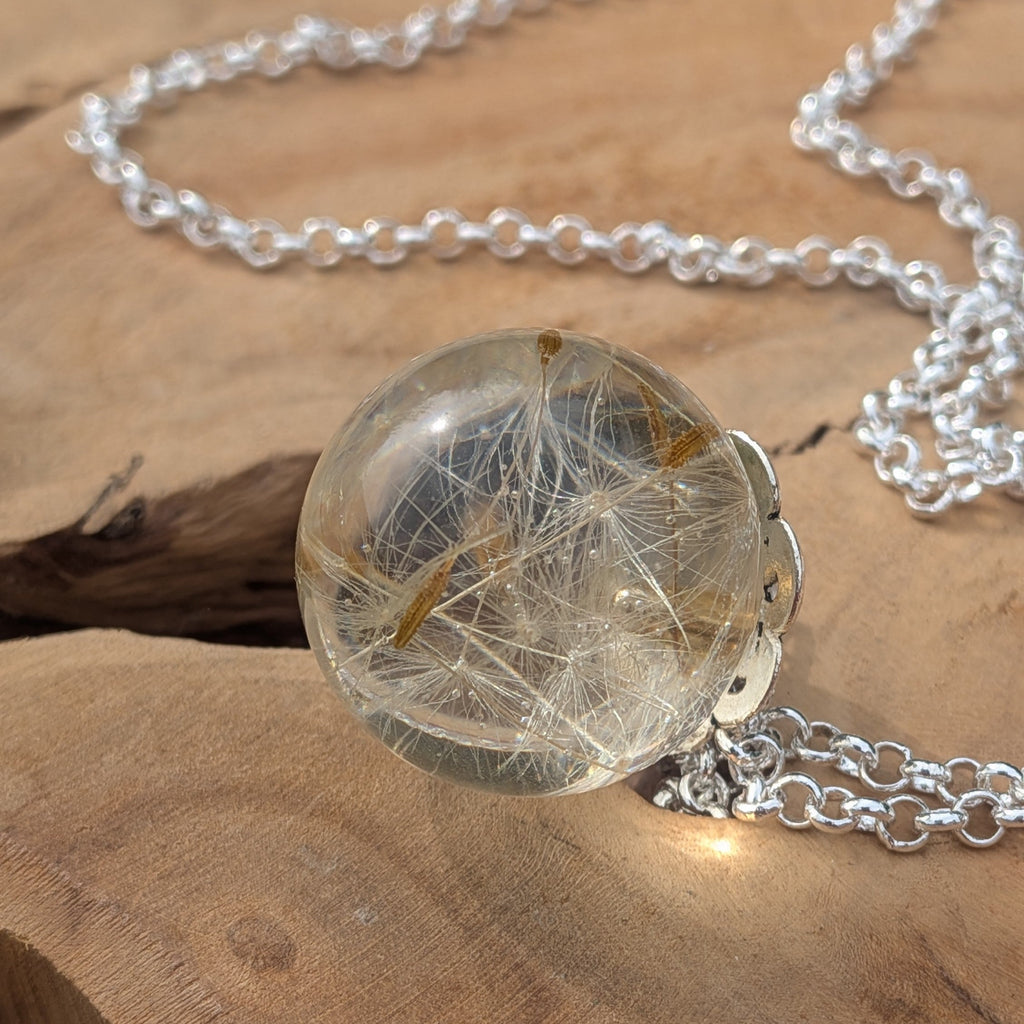 Close-up of preserved dandelion seeds inside clear resin ball pendant by EL-Creations