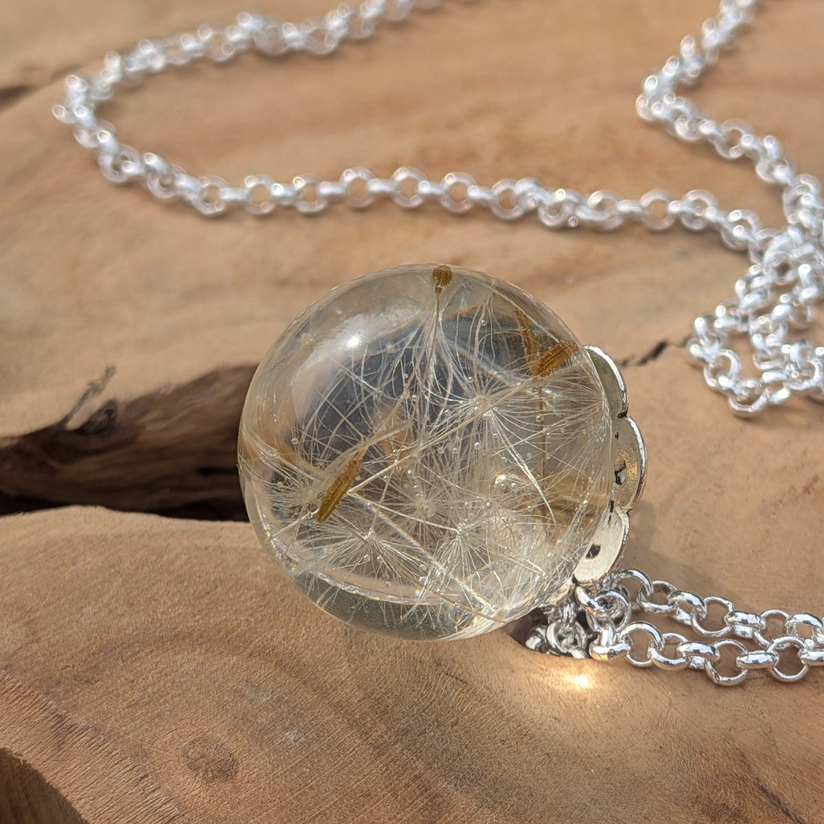 Close-up of preserved dandelion seeds inside clear resin ball pendant by EL-Creations