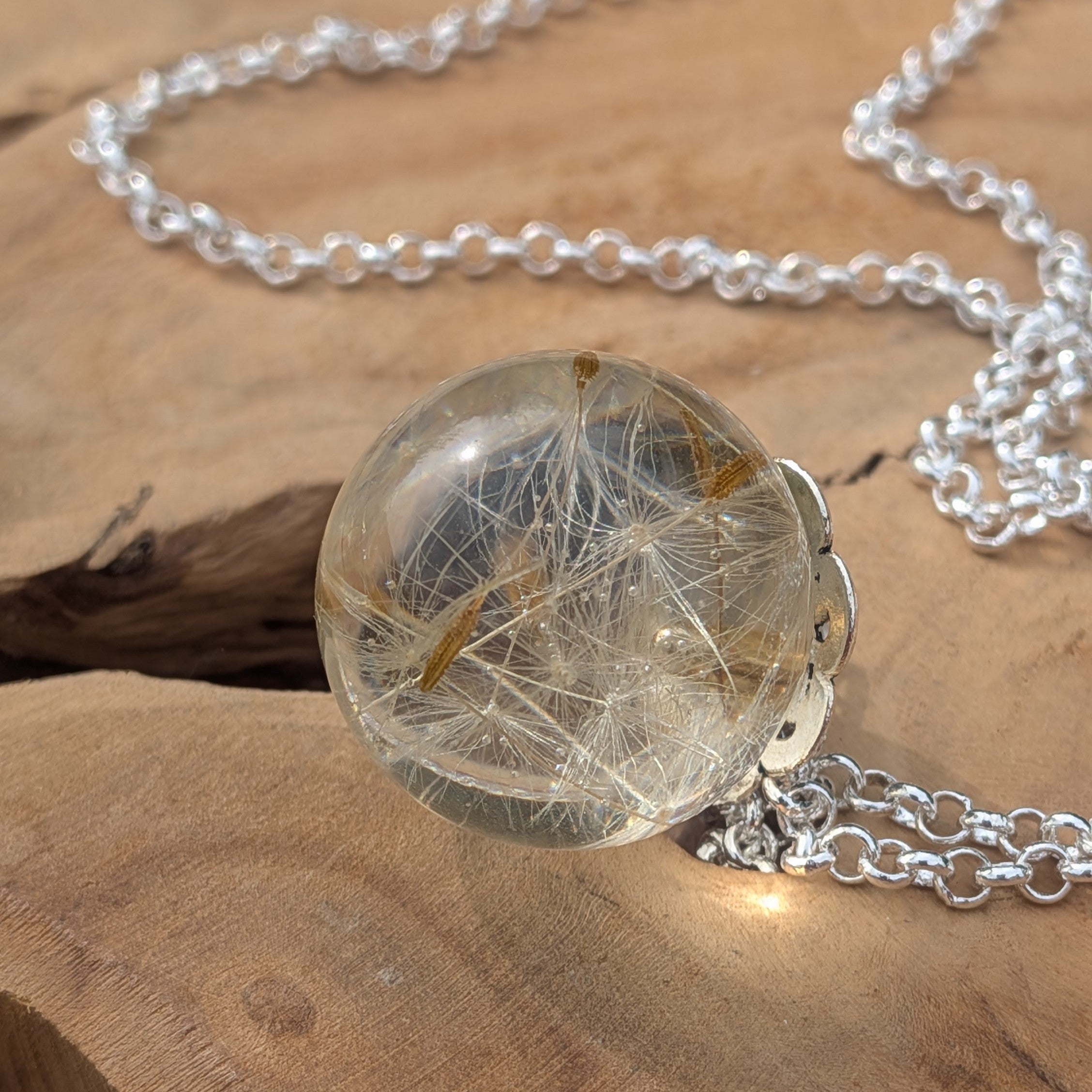 Close-up of preserved dandelion seeds inside clear resin ball pendant by EL-Creations