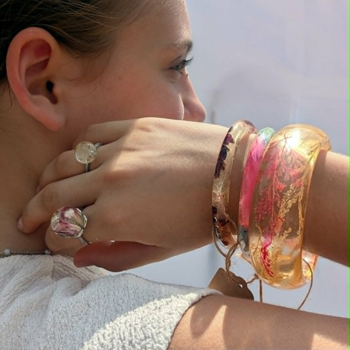 Woman wearing stacked amber and floral resin bangle bracelets and rings by EL-Creations