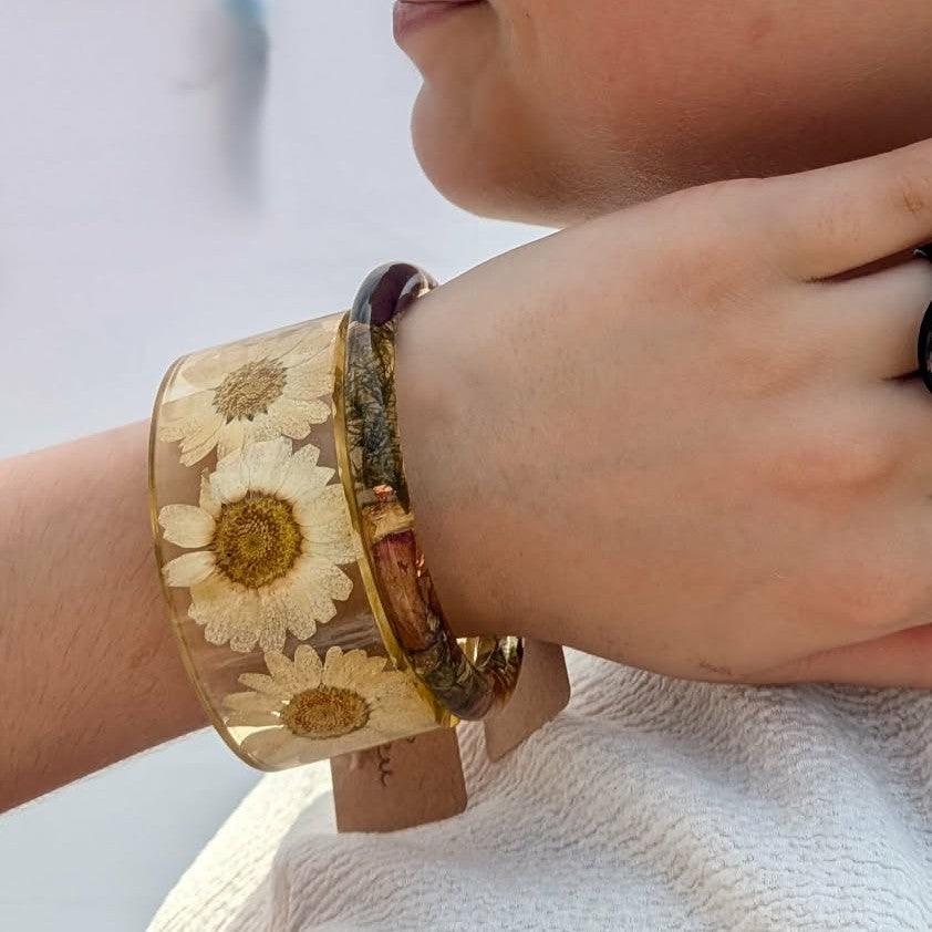 Wide clear resin bangle with real white daisy flowers held in sunlight by EL-Creations