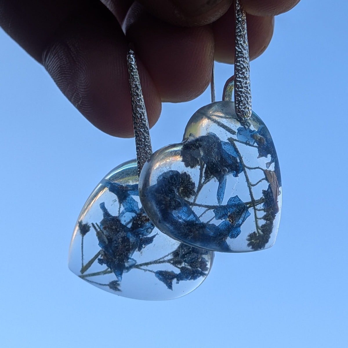 Handmade heart shaped earrings with blue forget-me-not flowers in clear resin by EL-Creations