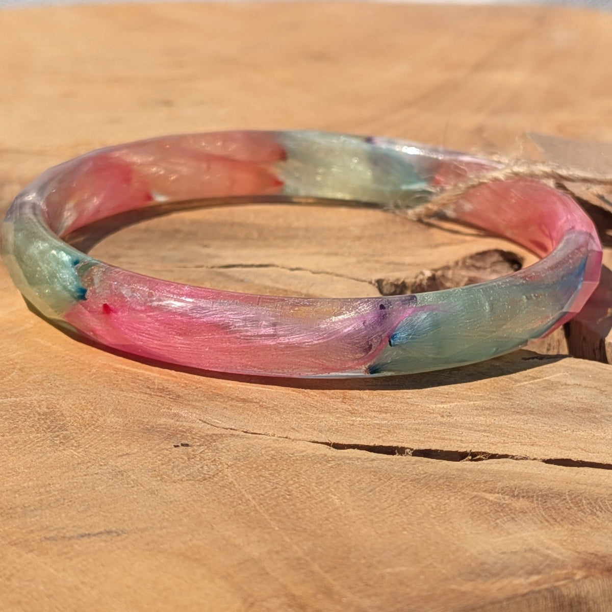 Close-up of pink and blue feathers inside clear resin bangle by EL-Creations