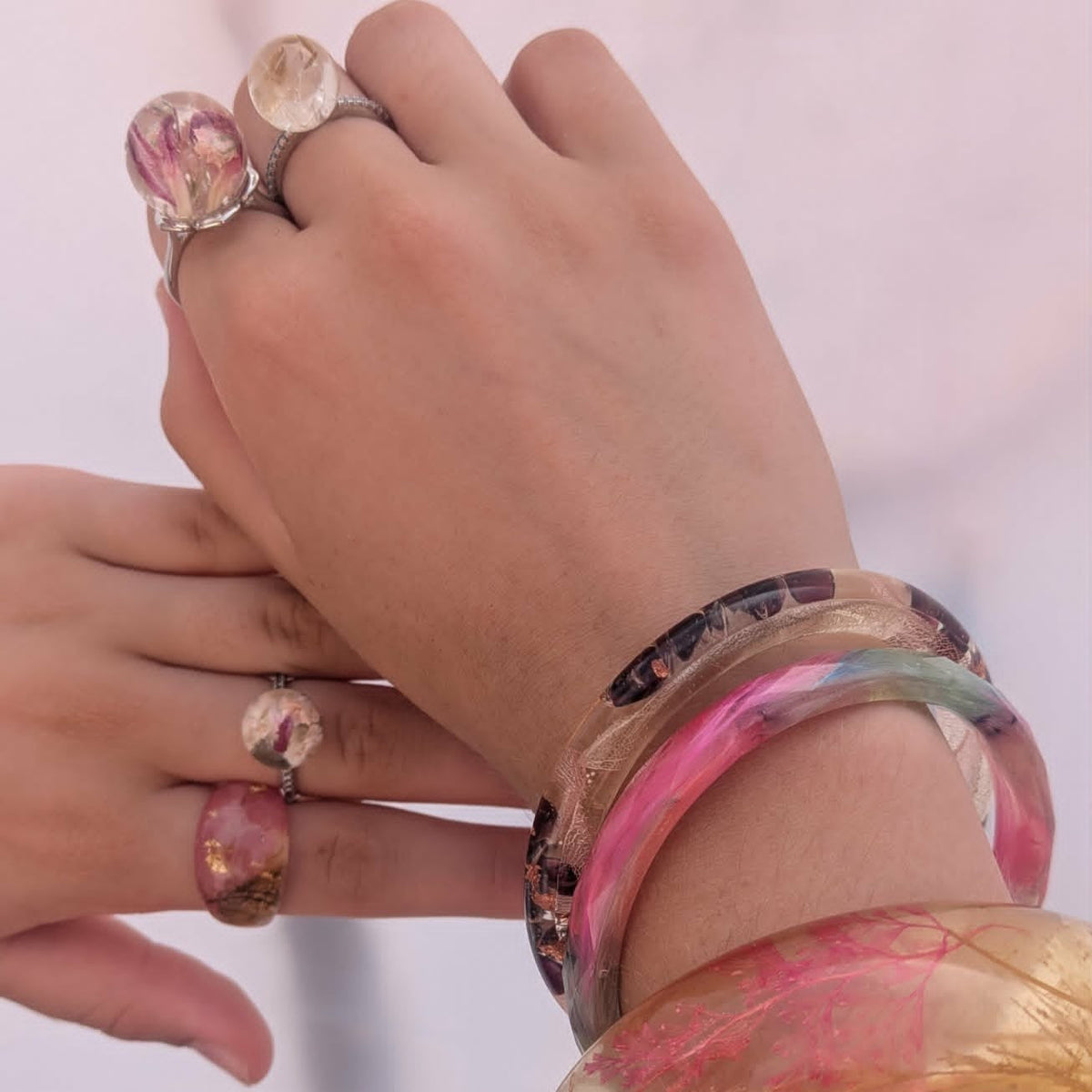 Woman wearing pastel feather resin bangle stacked with floral bracelets by EL-Creations