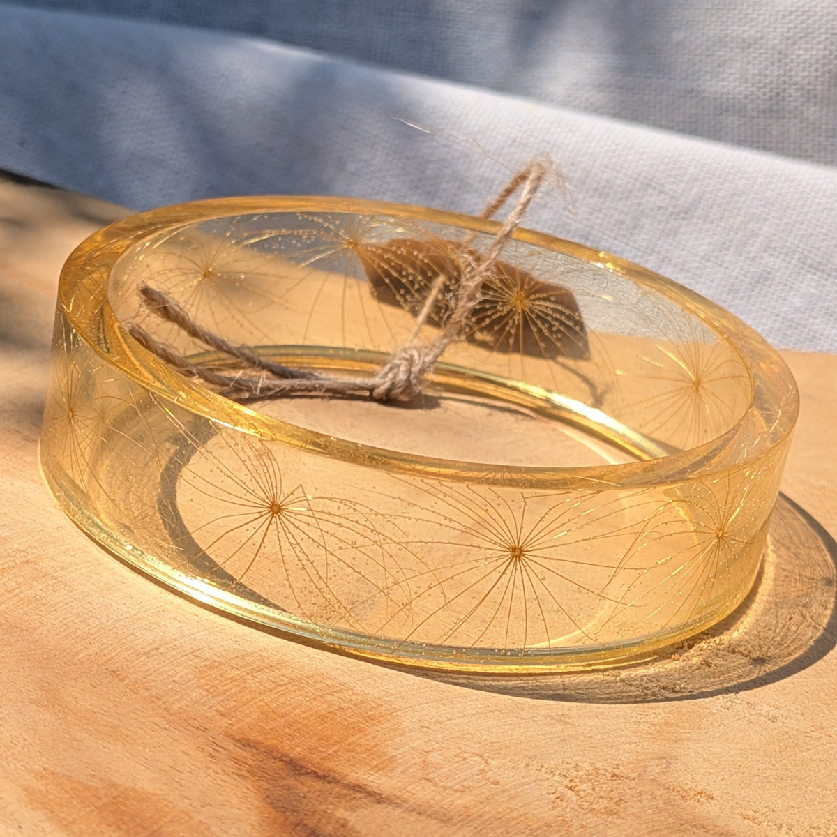 Wild wishflower seed resin bangle resting on wooden surface by EL-Creations